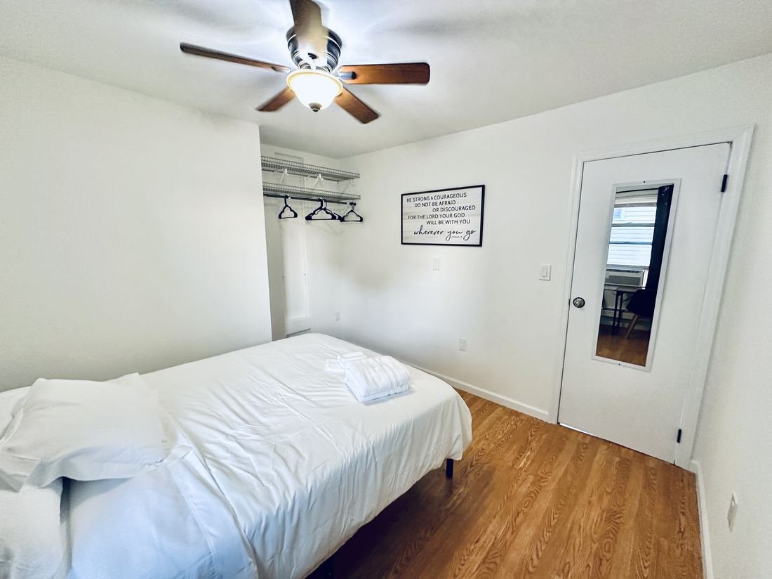 Bedroom with hardwood floors and white linens