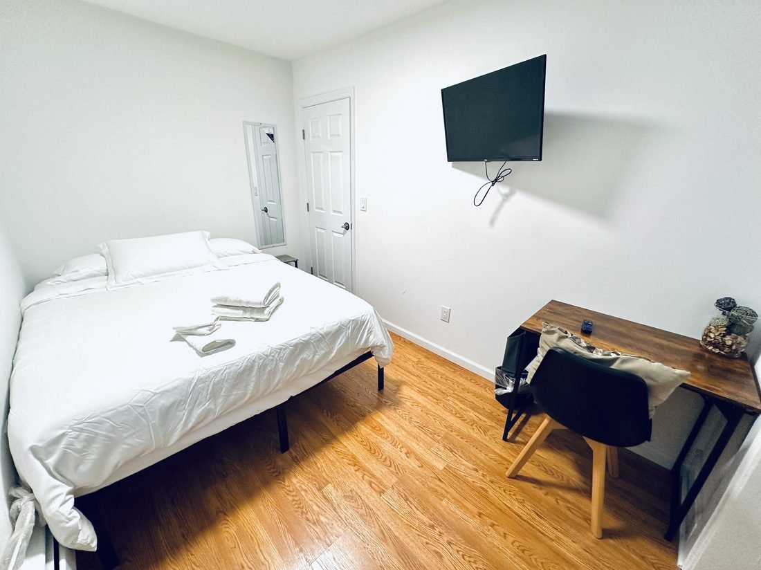 Bedroom with warm hardwood floors, made up with fresh linens